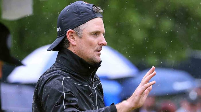 Justin Rose, hat backwards in the rain, waves to the crowd in the third round of the 2023 PGA Championship.